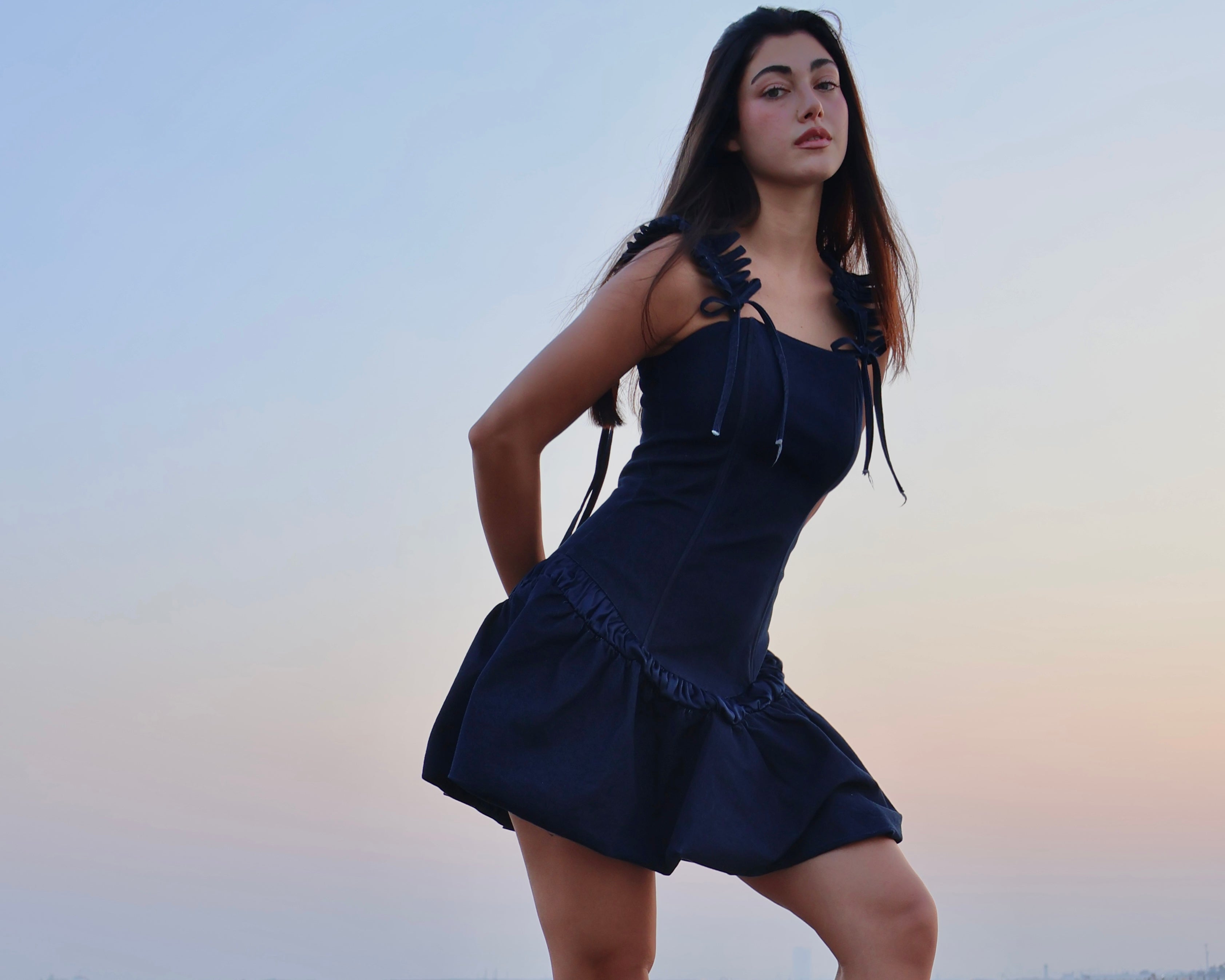 Model wearing the FRAEYA Navyra dark navy ruffled mini dress in an outdoor editorial setting.